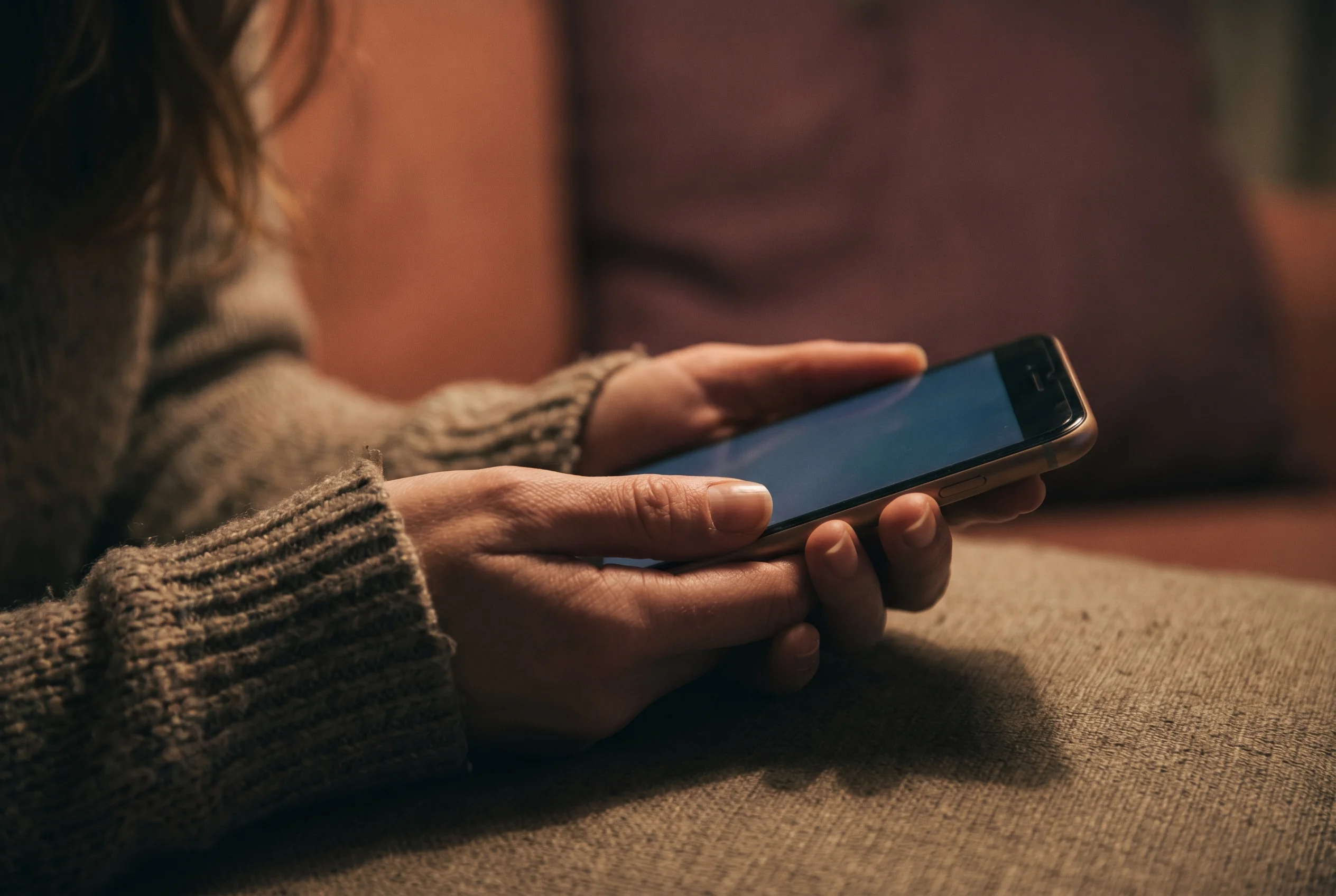 Mains d'une femme tenant un téléphone, dans l'attente d'un message