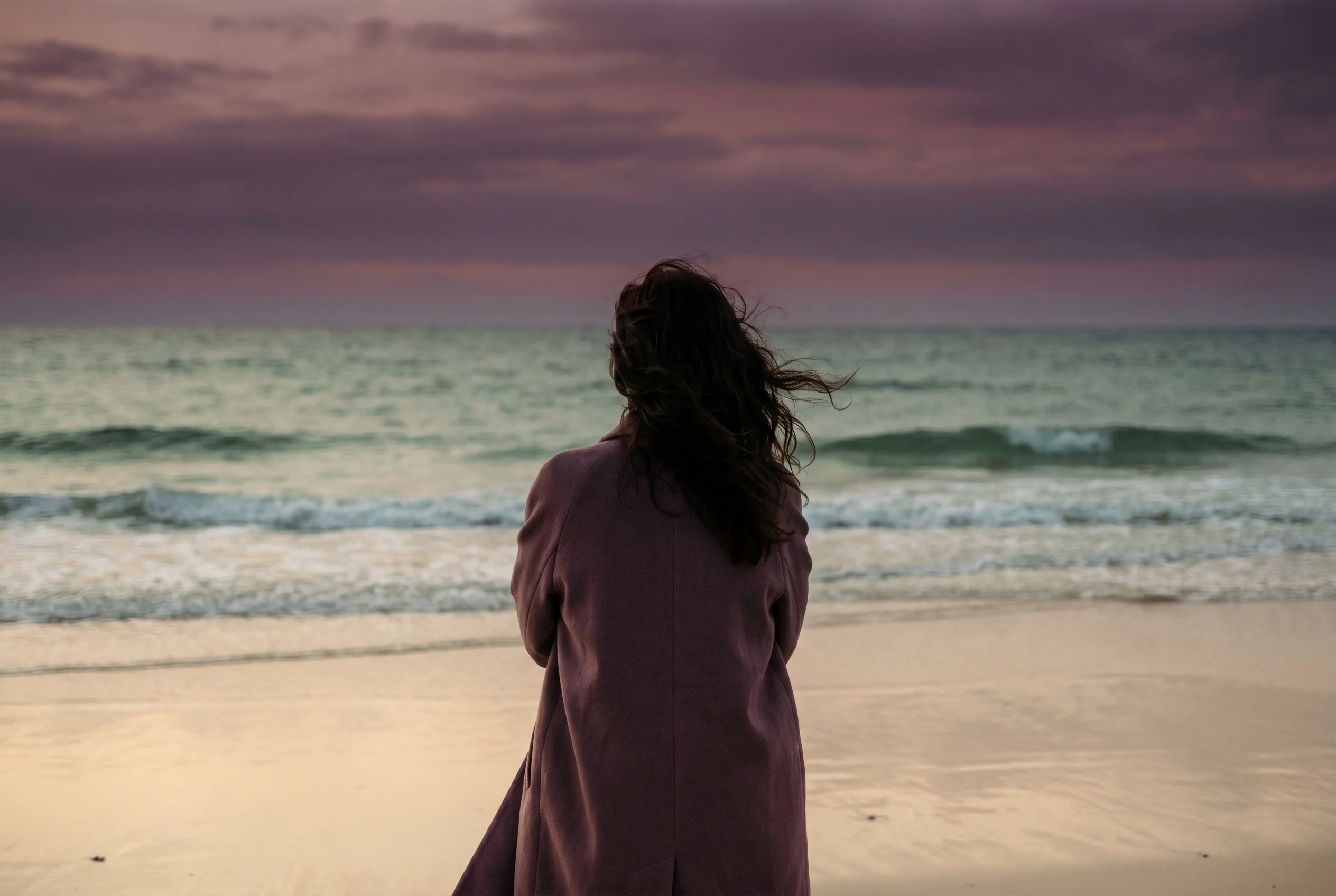 Femme de dos face à l'horizon, évoquant les vagues émotionnelles du deuil